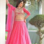 A beautiful Indian bride poses in a luxurious pink lehenga, showcasing traditional bridal fashion.