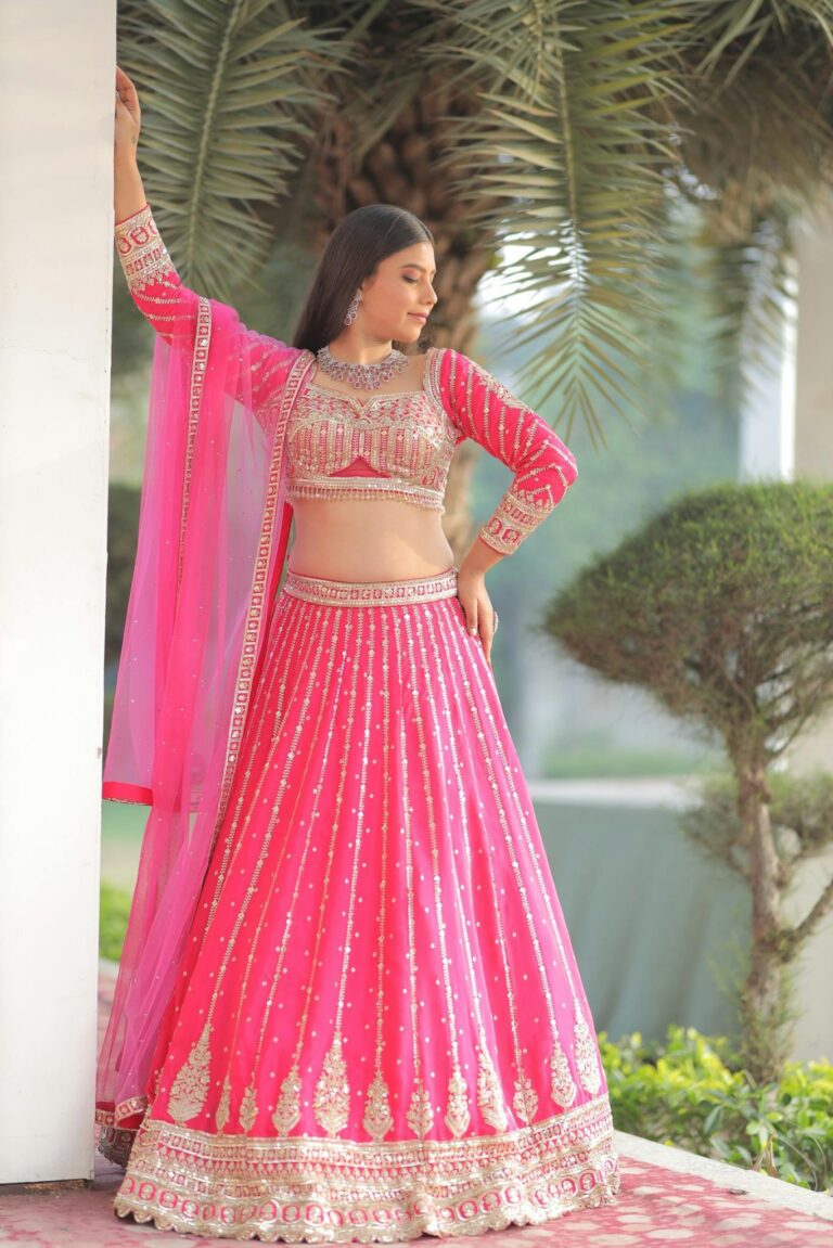 A beautiful Indian bride poses in a luxurious pink lehenga, showcasing traditional bridal fashion.