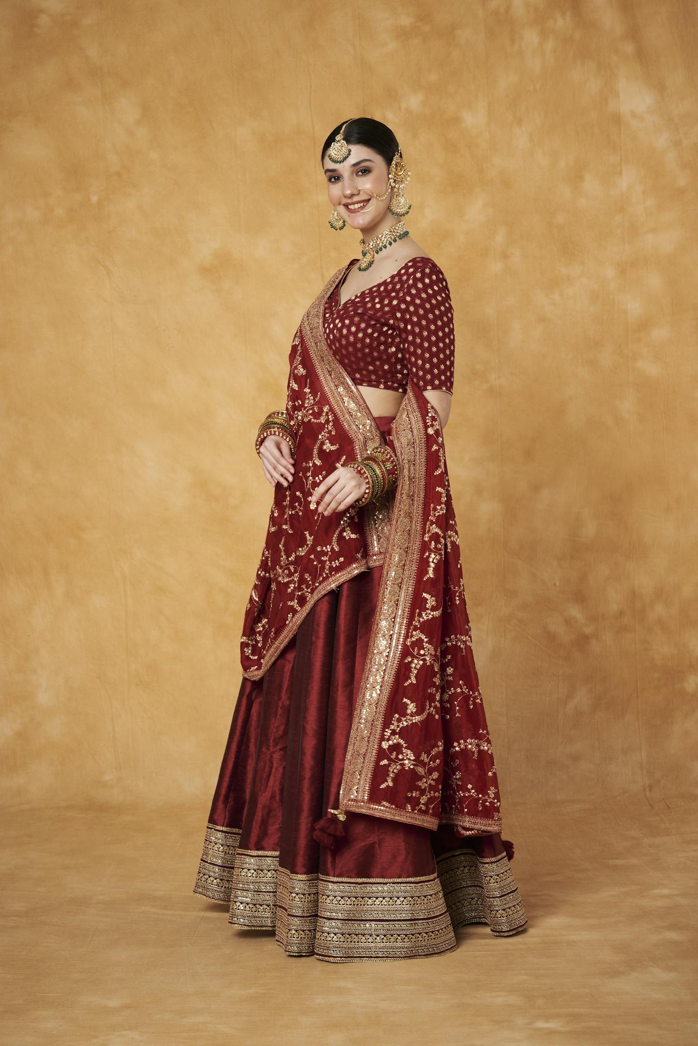 Elegant Indian woman in a red lehenga with intricate embroidery, posing with grace.