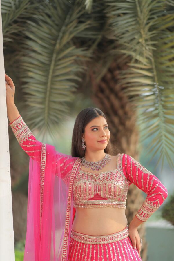 Stunning Indian bridal portrait with palm tree backdrop, wearing a pink lehenga.