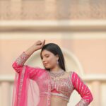 Stunning Indian bride in vibrant pink lehenga, posing gracefully at a historic Agra palace.