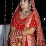 Stunning Indian bride wearing red lehenga and intricate jewelry at a wedding ceremony.