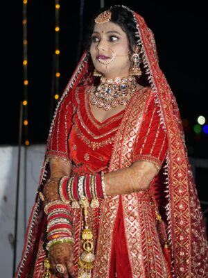 Stunning Indian bride wearing red lehenga and intricate jewelry at a wedding ceremony.