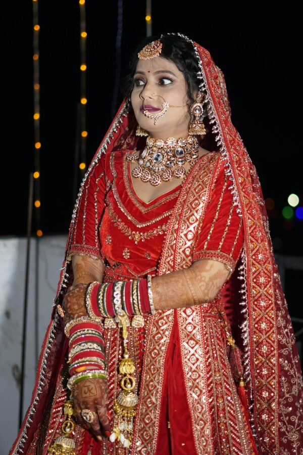 Stunning Indian bride wearing red lehenga and intricate jewelry at a wedding ceremony.